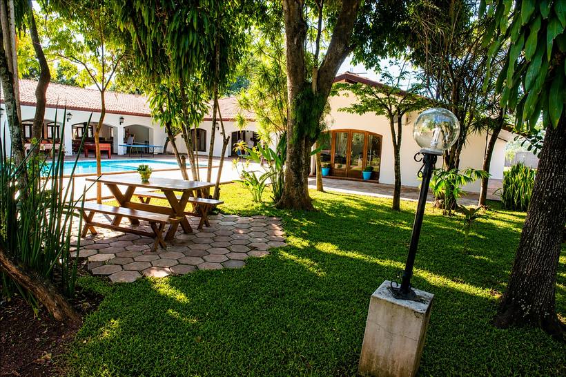 Piscina e área de convívio ao ar livre da Clínica Libertà, cercada por jardim.